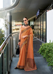 Woman in an orange saree standing on a modern building exterior