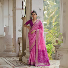 Woman draped in light pink Pochampali Ikkat saree with intricate zari weaving, styled with traditional jewelry in a heritage setting
