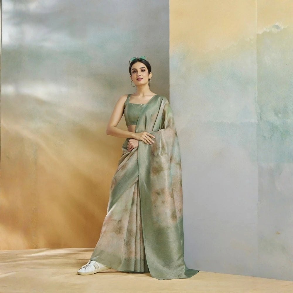 Woman in a green saree standing against a gradient wall
