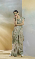 Woman in a light green saree standing against a neutral background