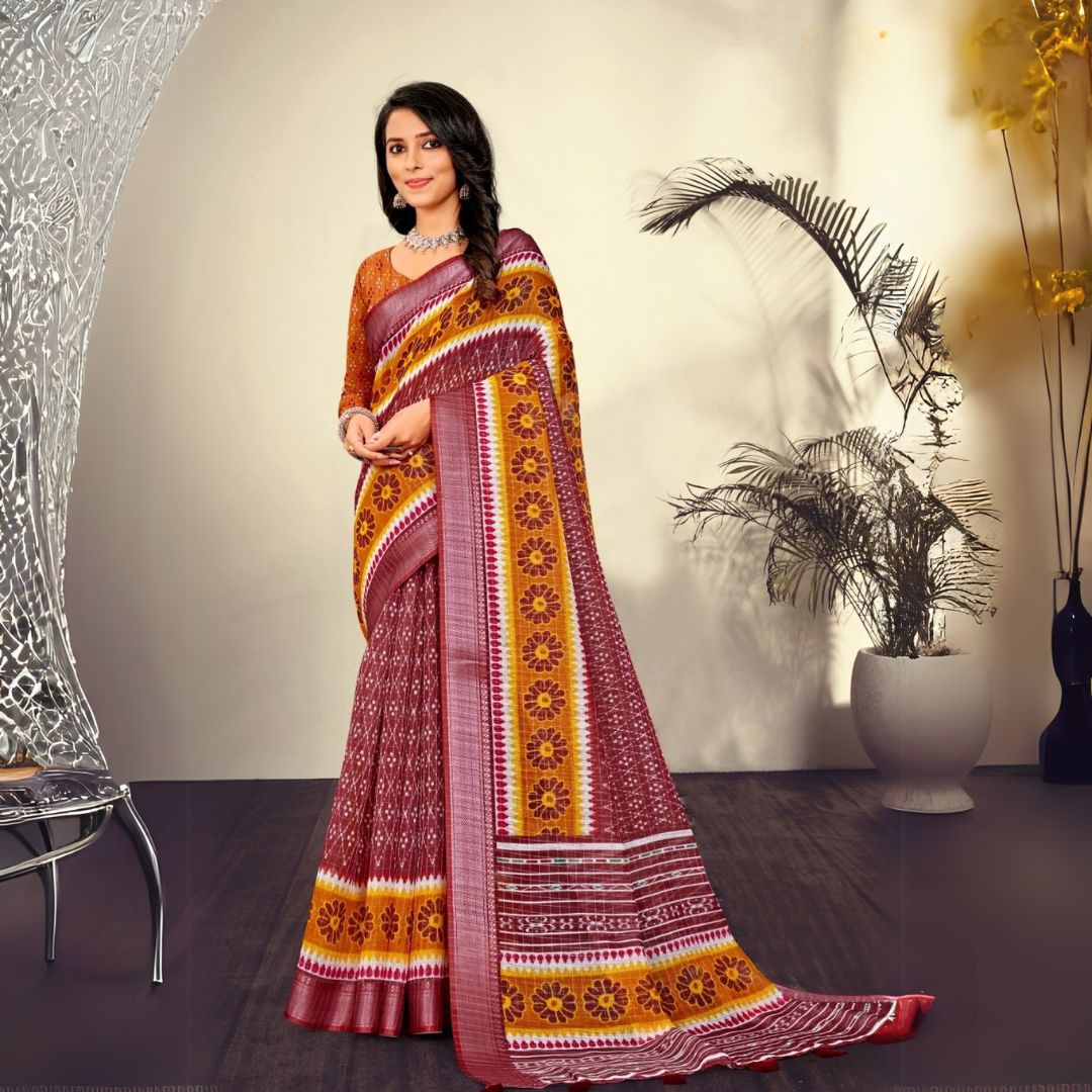 Woman in a maroon traditional printed pattern saree standing indoors with potted plants and modern decor in the background