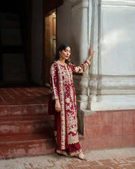 Woman in a red and gold traditional outfit standing in front of a marble wall.