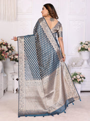 Woman holding a traditional saree with a white and blue pattern in a decorated room.