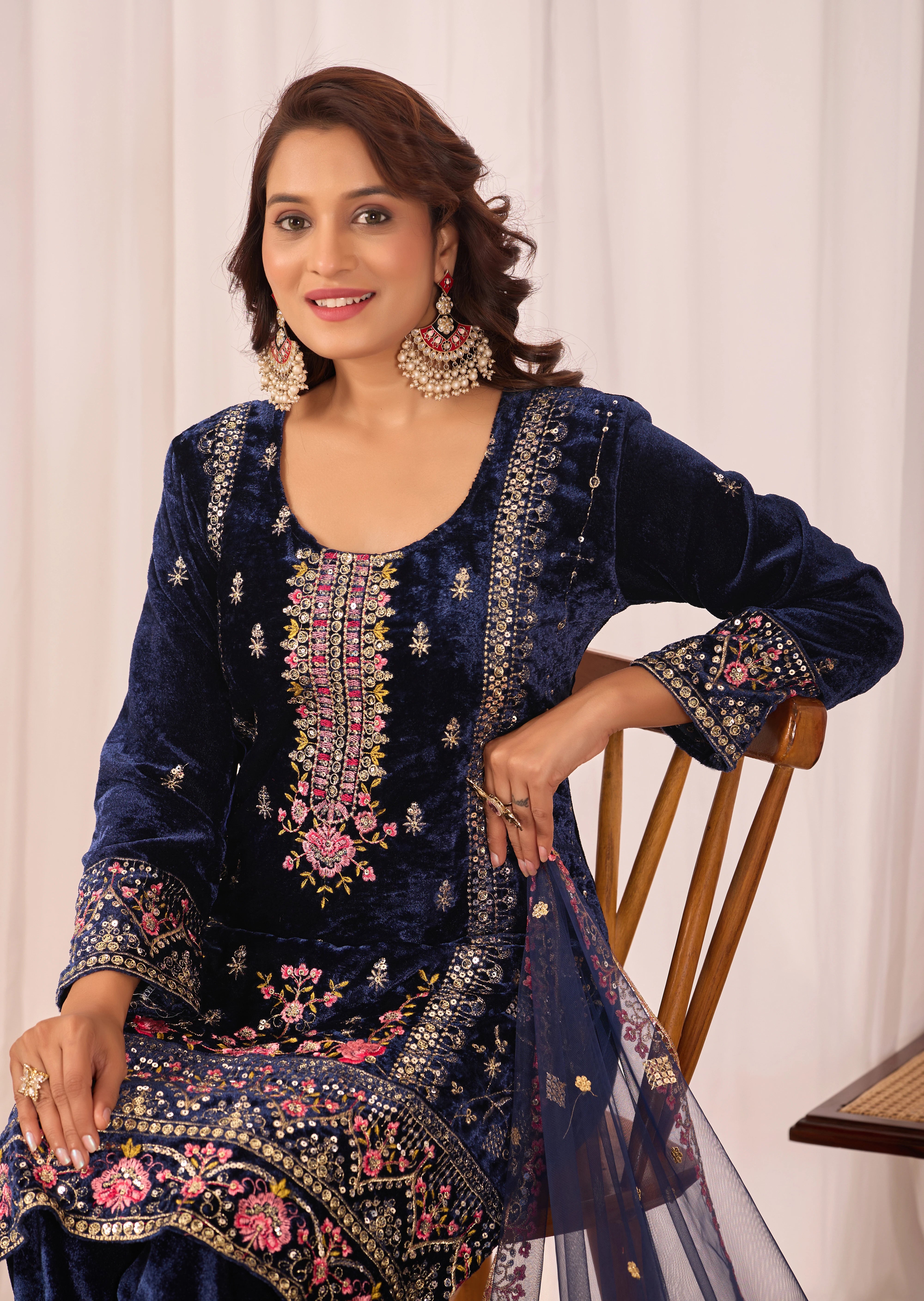 Woman wearing a navy blue embroidered traditional outfit with a white background