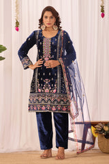 Woman wearing a navy blue embroidered traditional outfit with a white curtain background