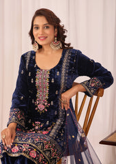 Woman wearing a navy blue embroidered traditional outfit with a white background