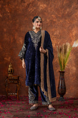 Woman in traditional navy blue and gold outfit with a textured brown background