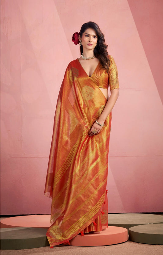 Woman wearing a traditional orange saree with a pink background