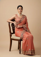 Woman in a traditional saree sitting on a chair against a beige background