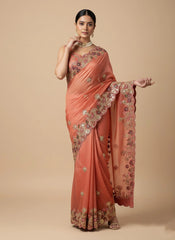 Woman wearing a peach saree with floral patterns on a beige background