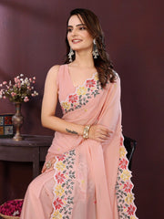 Woman wearing a pink saree with floral patterns against a dark background