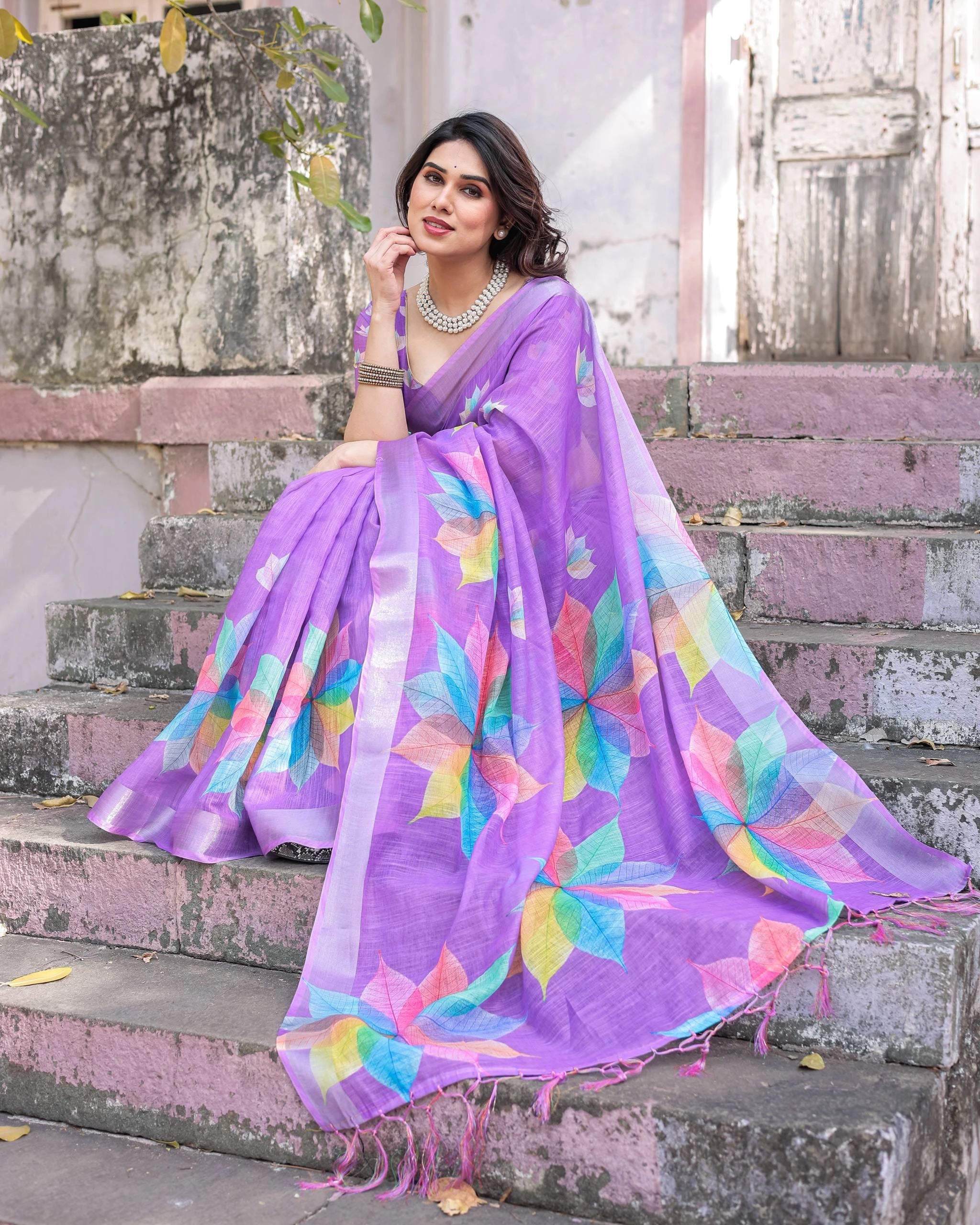 Woman wearing a colorful saree with a floral pattern on steps.