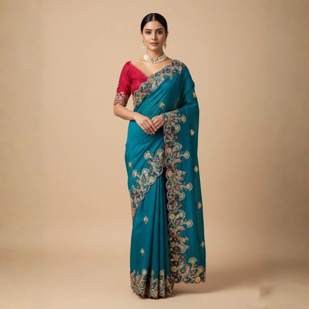 Woman wearing a blue saree with intricate patterns on a beige background