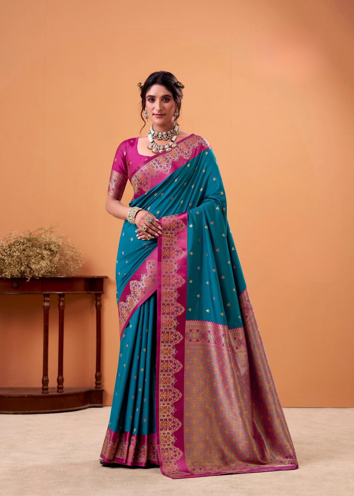 Woman wearing a blue and pink saree with a matching blouse against an orange background