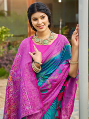 Woman wearing a colorful saree with a vibrant pink and blue pattern, standing outdoors.