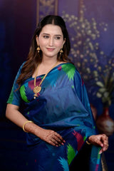 Woman in a blue saree with colorful patterns against a decorative background