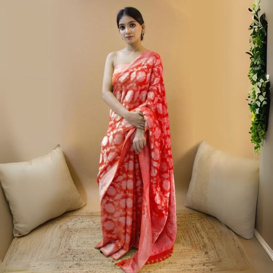 Woman in a red jacquard work saree with gold border standing indoors in a refined room with arched decor and vintage furniture accents