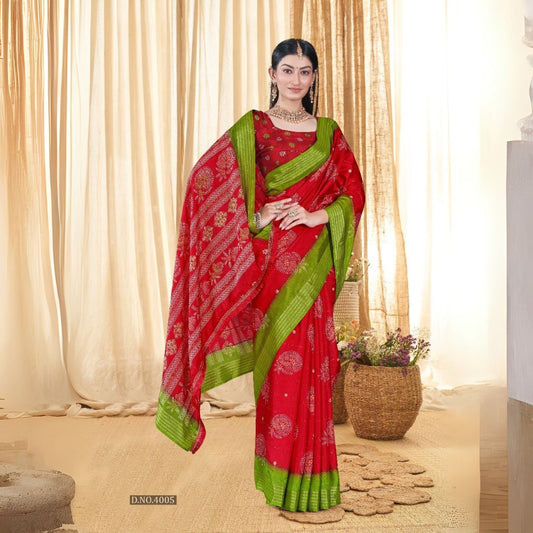 Woman in a red sequence jacquard work saree with green border standing indoors against a backdrop of beige curtains and woven decor elements