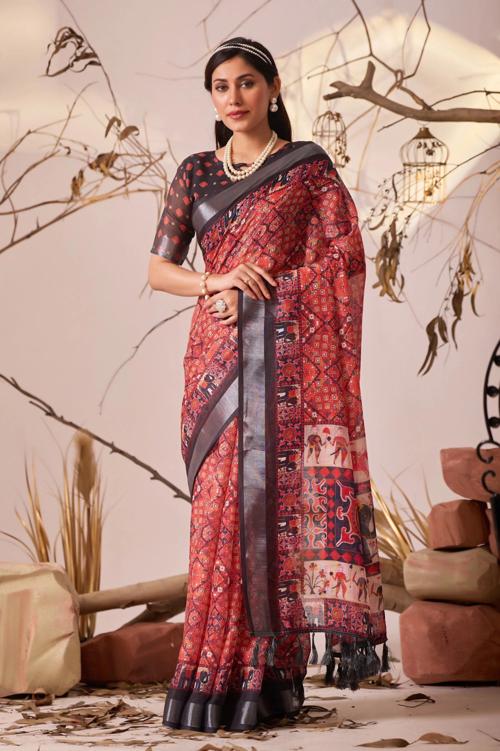 Woman wearing a red patterned saree with a black blouse in an indoor setting.