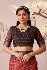 Woman wearing a black and red patterned blouse with a matching skirt against a neutral background
