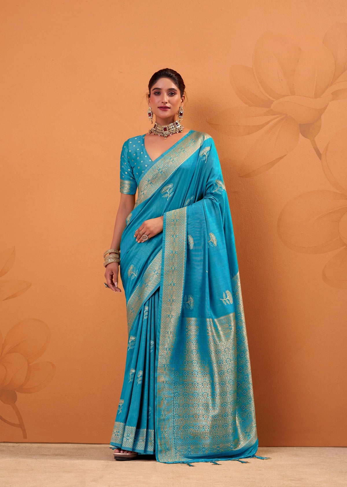Woman wearing a blue saree with a gold border against an orange background