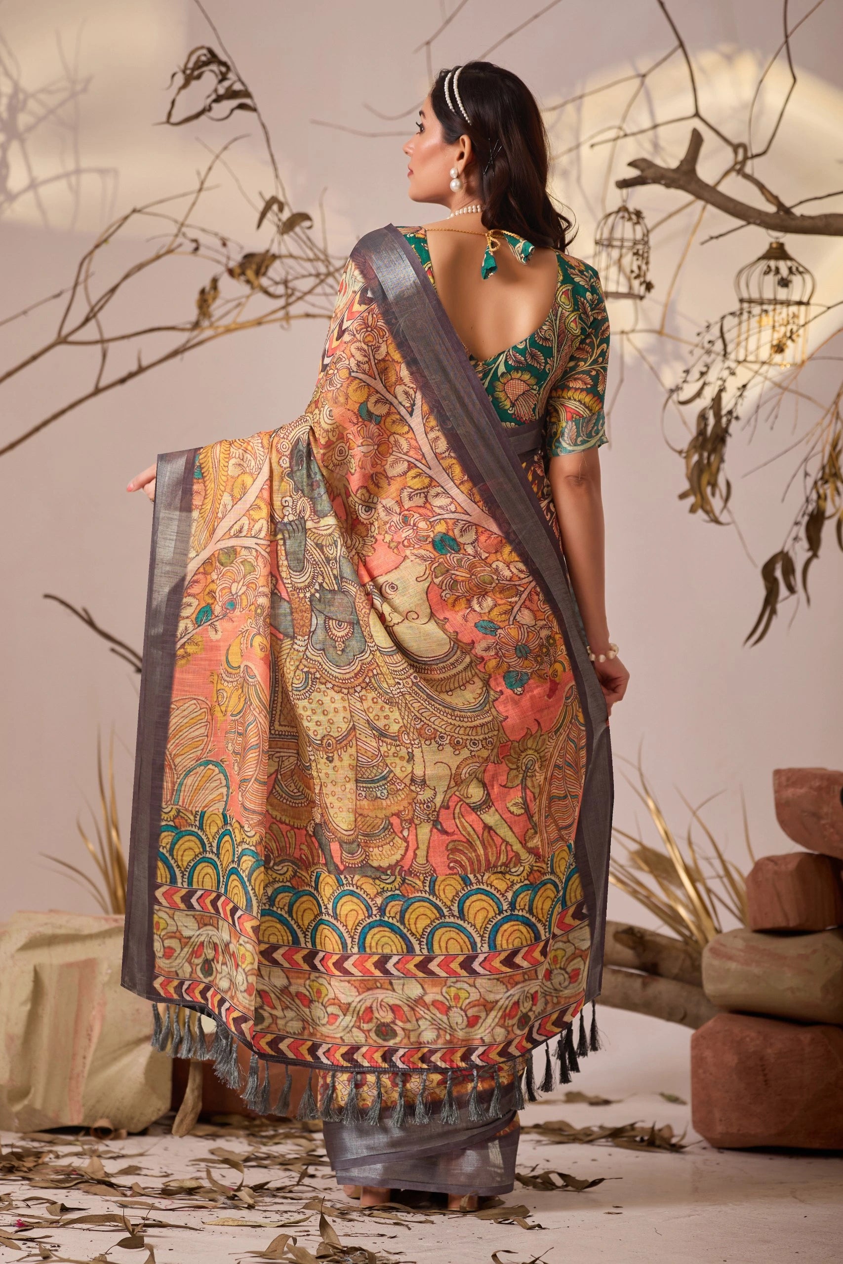 Woman wearing a traditional saree with intricate patterns in a decorative setting.