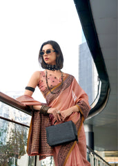 Woman in a pink saree with a black clutch standing in an urban setting.