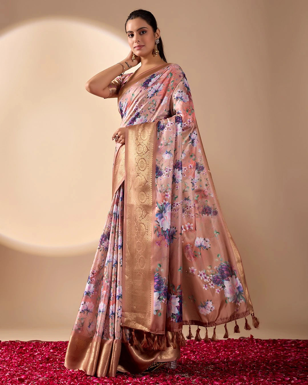 Woman wearing a floral saree with a gold border on a beige background