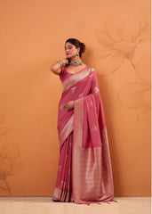 Woman wearing a pink saree with a subtle pattern against an orange background