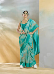 Woman wearing a teal saree with a gradient effect against a neutral background
