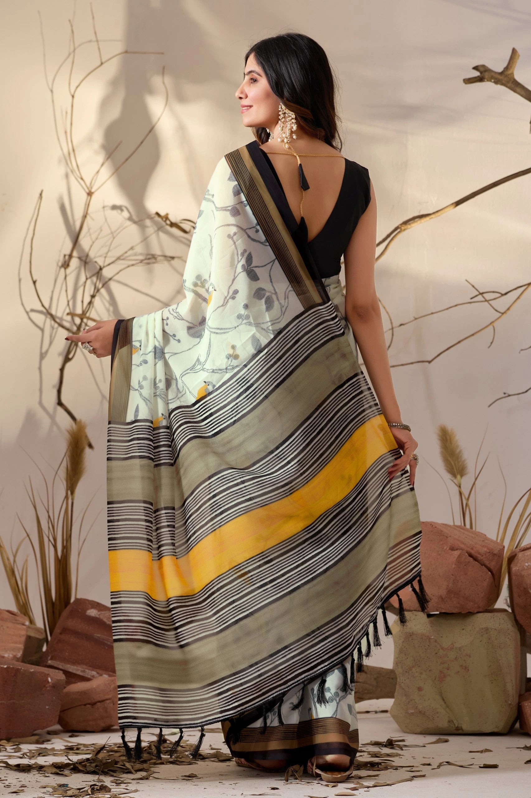 Woman wearing a saree with a patterned design, standing against a neutral background.