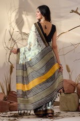 Woman wearing a saree with a patterned design, standing against a neutral background.
