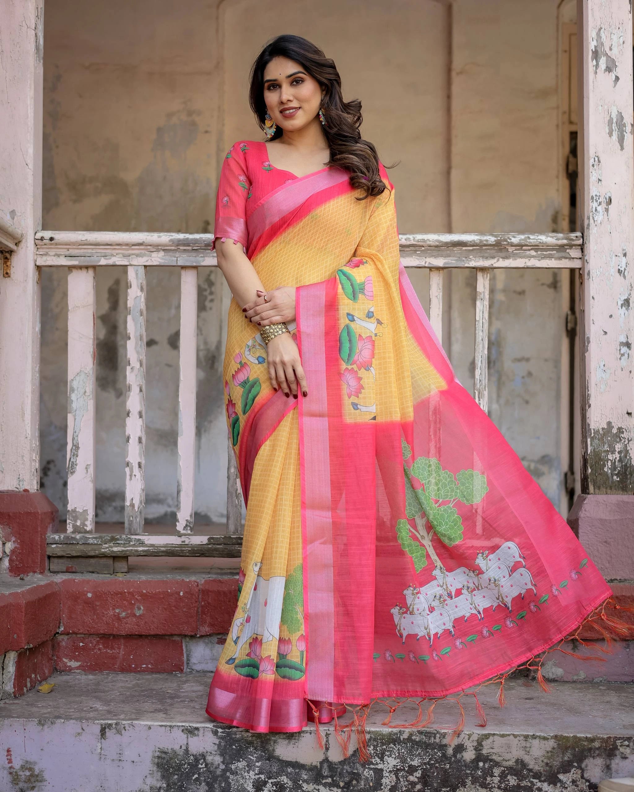 Woman wearing a yellow and pink saree with floral patterns on a rustic background