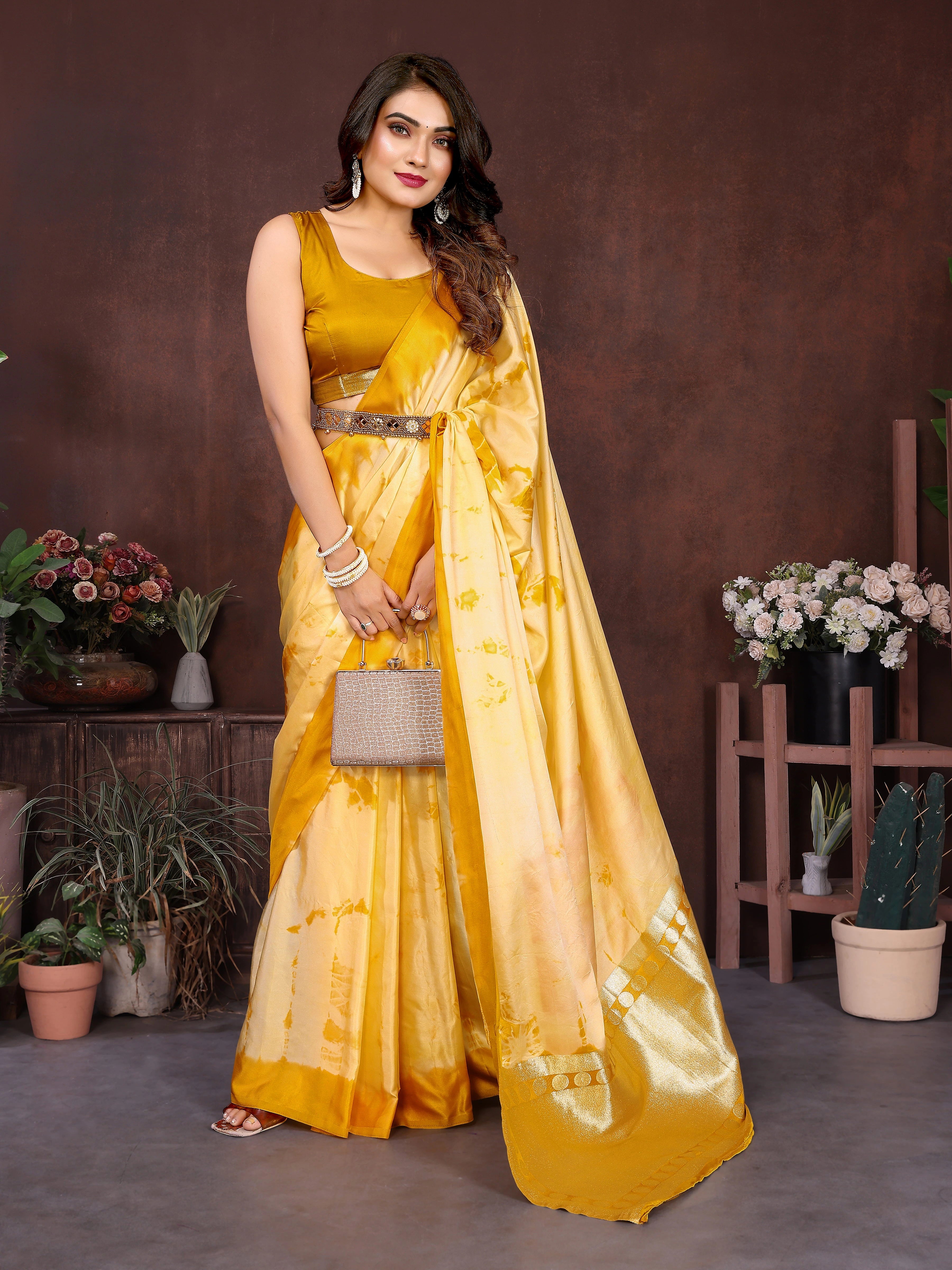 Woman wearing a traditional saree in a decorated room with flowers and white furniture.