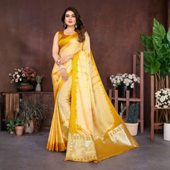 Woman in a yellow saree standing in a room with plants and flowers.