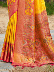 Traditional yellow and red saree with intricate patterns on a natural background