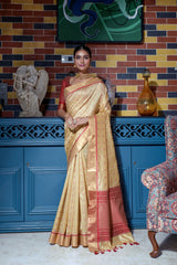 Beige saree with zari work and red border indoors