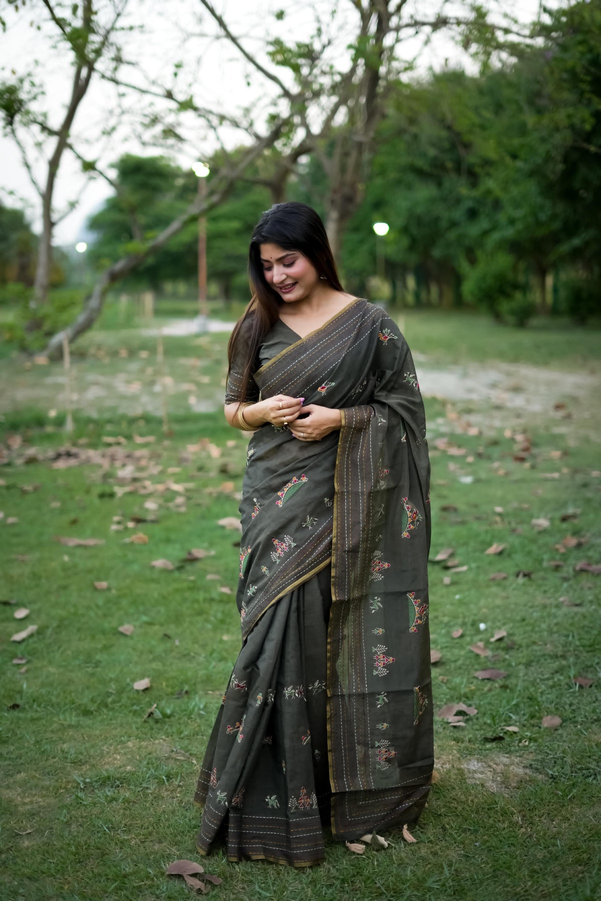  Woman in black traditional weaving saree showcasing elegant style in a garden setting