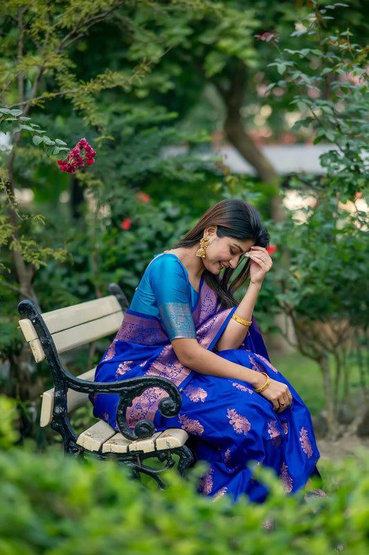 Woman in blue saree with zari work sitting in garden