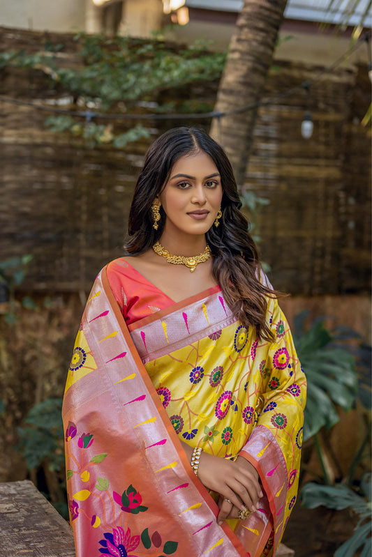 Close-up of woman in brown yellow zari work saree with intricate floral pallu, styled with traditional gold jewelry in an outdoor setting
