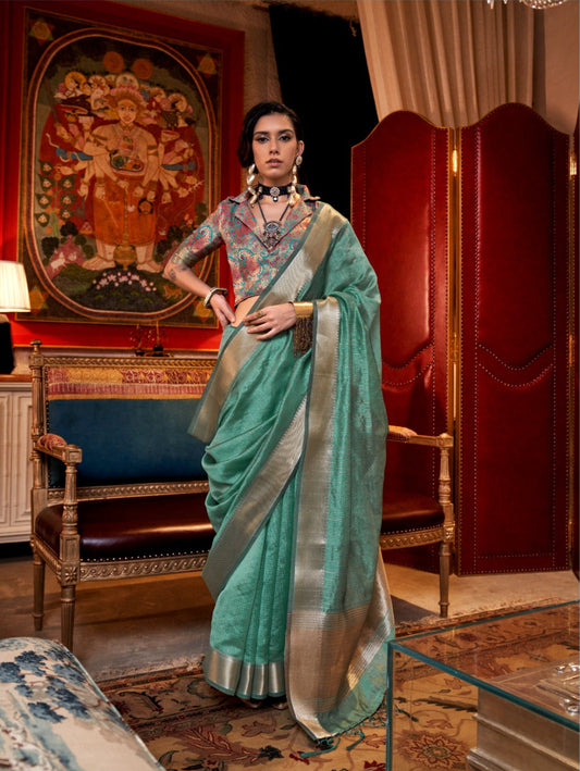 Model in deep teal saree with elegant zari work and colorful embroidered blouse, showcasing luxurious ethnic fashion in a regal setting