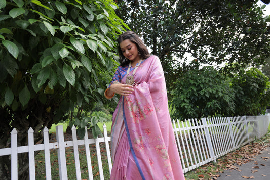 Woman wearing light pink floral print saree standing outdoors in elegant traditional Indian ethnic outfit