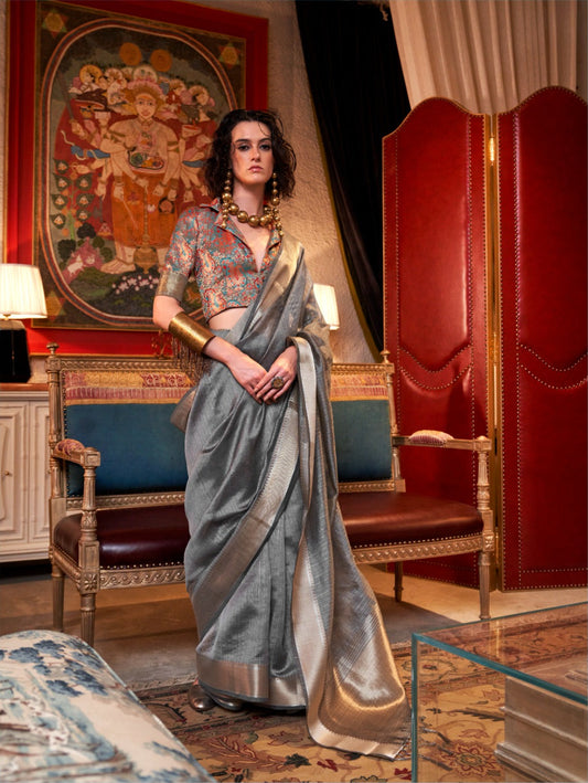 Elegant woman standing in gray zari work saree with intricate blouse and bold accessories showcasing traditional style