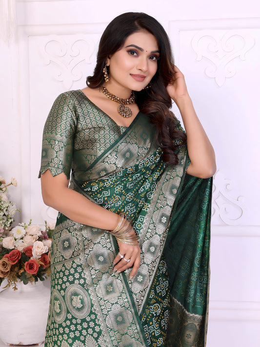 Woman wearing a green Banarasi silk saree adorned with intricate silver zari border and traditional woven motifs, paired with a matching silver blouse and classic jewelry. She poses gracefully in an elegant white room with decorative wall panels, white vases, and abundant pastel floral arrangements.