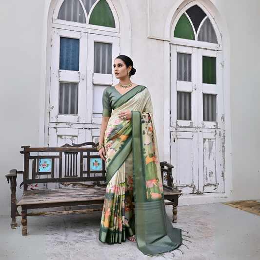  Woman wearing a green floral saree with intricate patterns and a matching green blouse, accessorized with traditional gold jewelry including a statement necklace, standing beside a vintage wooden bench in front of weathered white doors with green and blue stained glass panels in a heritage-style courtyard setting.