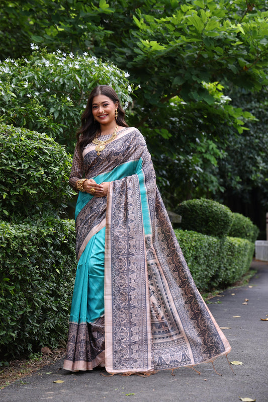 Woman wearing traditional powder blue Madhubani print saree with intricate designs and ethnic jewelry in a green outdoor setting