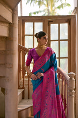 Woman wearing a magenta silk saree with teal pallu and intricate floral motifs, paired with matching blouse and traditional earrings, elegantly posing beside a vintage spiral staircase in a sunlit heritage interior with large wooden windows, distressed textured walls, and geometric patterned tile flooring.