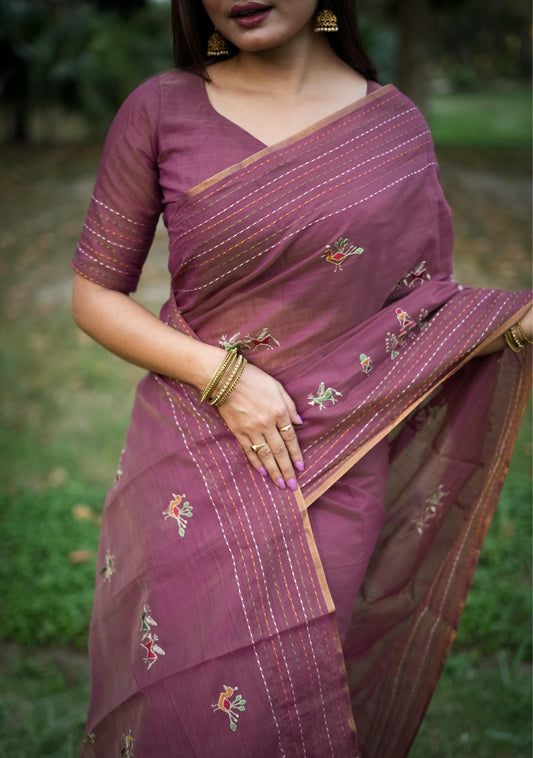 Woman in magenta traditional weaving saree with delicate motifs posing gracefully in a natural outdoor setting.