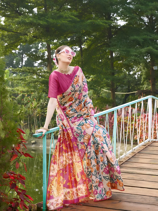 Woman wearing a multicolor saree with vibrant Madhubani-inspired floral and paisley prints, paired with a matching blouse and traditional jewelry, gracefully standing on stone steps beside a wooden bridge surrounded by lush greenery and red flowering plants in a garden setting.