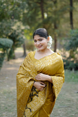 Smiling woman in mustard yellow saree with zari work